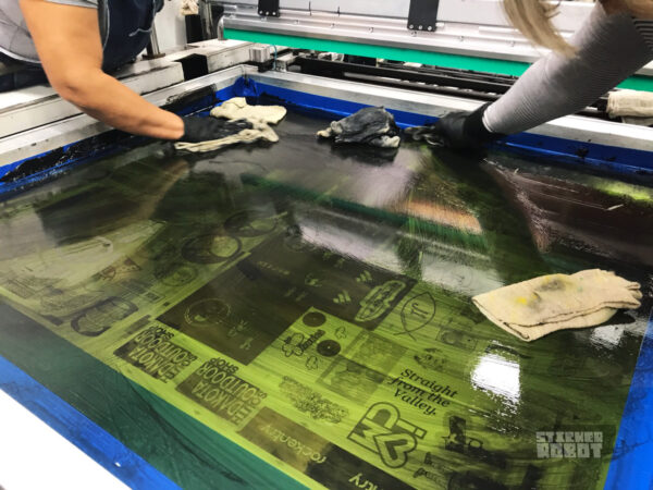 Close view of ink being cleaned from screens on a silkscreen press